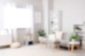 Blurred view of light living room with sofa and soft bench