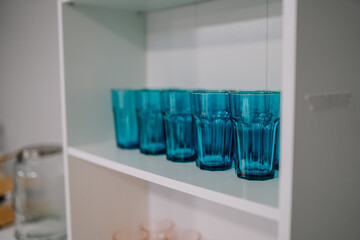 Cozy interior with stylish furniture and modern design. Empty stylish glasses on shelf unit near wall