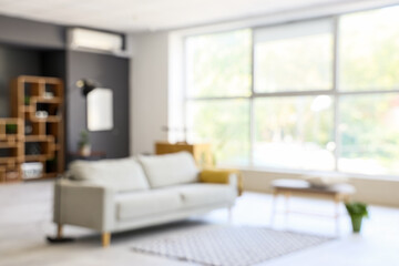 Blurred view of modern living room with sofa and soft bench