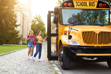 Group of happy kids boarding yellow school bus after lessons - obrazy, fototapety, plakaty