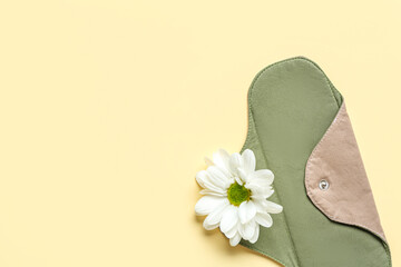 Reusable menstrual pad and chamomile flower on color background © Pixel-Shot