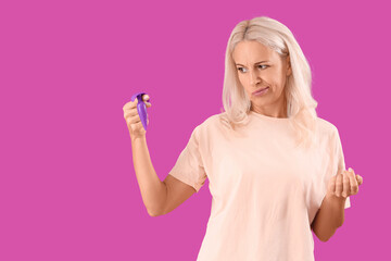 Thoughtful mature woman with anal plug on purple background