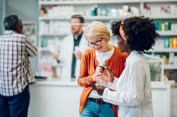 African american woman pharmacist talking to a senior customer in a pharmacy