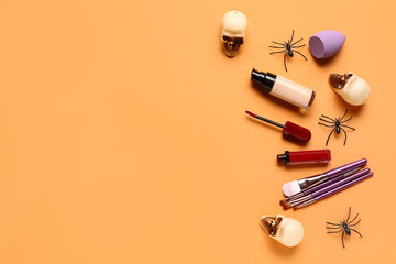 Lipstick and different decorative cosmetics with Halloween decor on orange background
