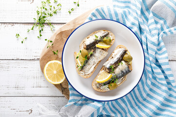 Sardines sandwiches on a white wooden background. Mediterranean food. Top view - 664063131