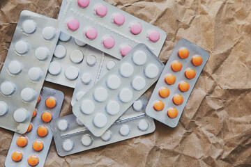 Different blisters with tablets: painkillers, vitamins, herbal preparations, prescription and over-the-counter medications. Packages of tablets on craft paper. Tablets, top view. Selective focus