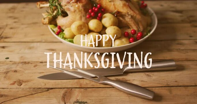 Animation of happy thanksgiving over dinner food and cutlery on wooden background