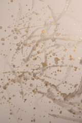 Gold, silver glitter Ink watercolor drop blot on beige paper texture background.