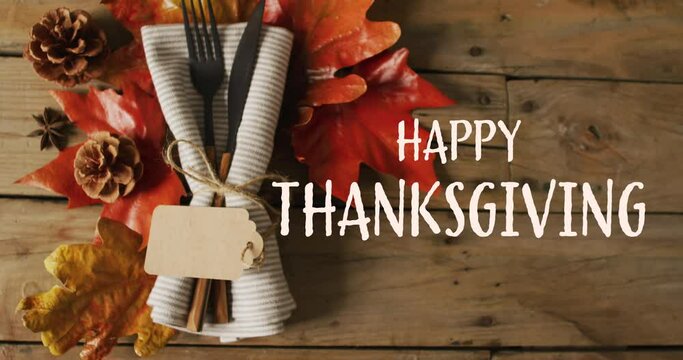 Animation of happy thanksgiving over place setting on wooden background