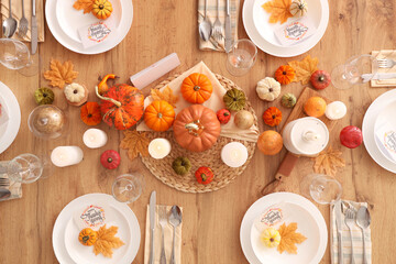 Festive table setting for Thanksgiving Day with pumpkins, greeting cards and candles