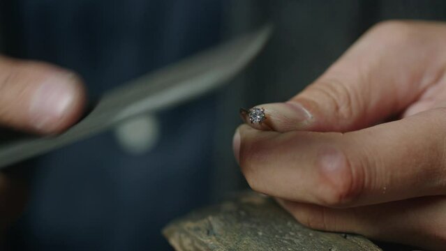Male jeweler shaping prong setting of gold ring