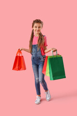 Little girl with shopping bags on pink background