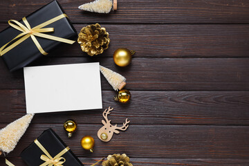 Beautiful Christmas composition with blank card, gift boxes and decor on black wooden background