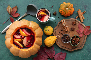 Beautiful composition with tasty mulled wine in pumpkin on green background