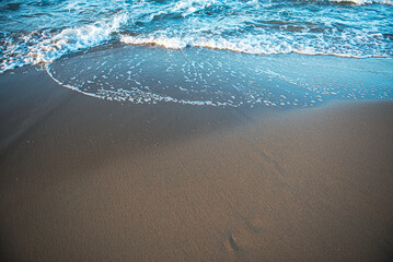 A wave runs aground on a brown sand beach