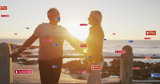 Animation of social media text and icons over caucasian couple on beach