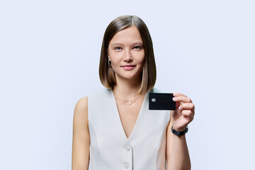 Young woman with bank credit card in hands on white studio background.