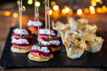 Christmas canapes with blinis with salmon, beetroot and goat cheese and filo pastry cups - obrazy, fototapety, plakaty