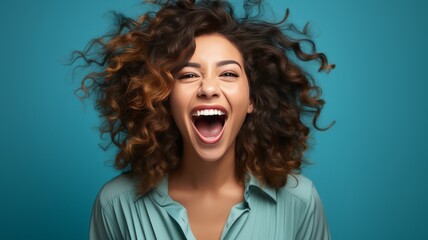 Happy woman with curly brown hair smiling broadly on blue background