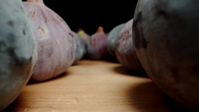 On a wooden table, there are ripe Figs. The camera glides along its rows. Dolly slider extreme close-up.
