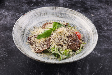 Salad of meat, lettuce, tomatoes, fennel and bresaola on a light wood surface. and cheese