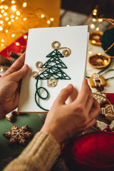 Guide for children how to make postcard with paper Christmas fir tree. Holiday idea for family time. Fine motor skills, creativity development and fun. Lights on background, gingerbread cookies