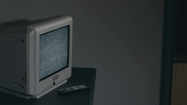 Broken Television - Old Silver TV on Black Table in Dark Room. Search for Signal. Distortion on the Screen. Close-Up, Dinamic Shot, Film Grain