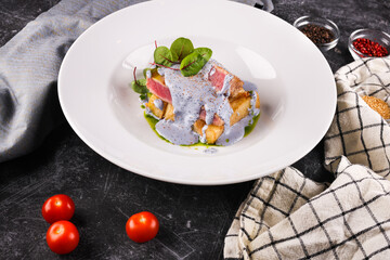 grilled tuna with greens on a white plate on a dark background