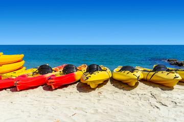 Red and yellow kayaks on the beach with the ocean and sky in the background