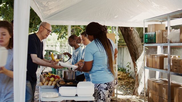 At food drive, organized by non-profit, gathers diverse group of individuals committed to aiding the homeless and less fortunate. Volunteers generously provide hot meals to those in need. Handheld