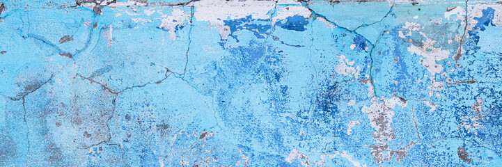 Vintage wall texture. Rough surface of the plastered concrete wall of the building. A pattern with many cracks and old faded peeling paint. Wide panoramic texture for background and design.