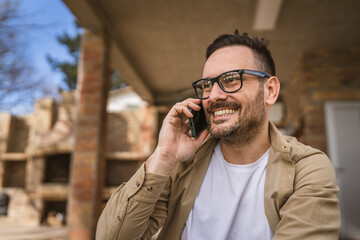 One adult man in front house in day use smart phone talk make a call