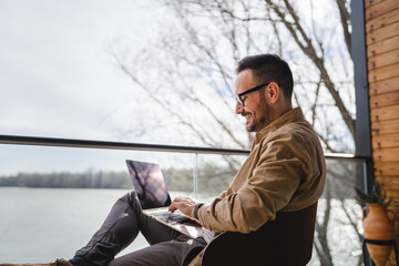 man caucasian work on laptop computer on terrace happy smile success
