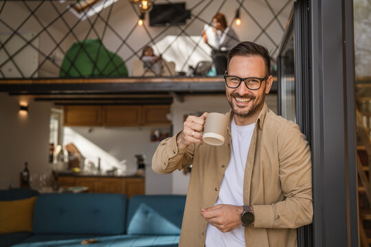 One adult man stand in at door of tiny house happy smile hold cup