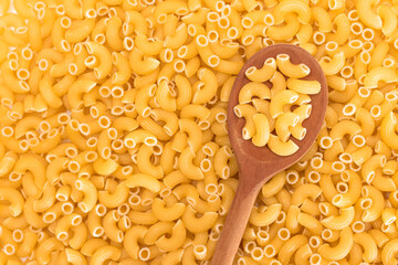 Uncooked Chifferi Rigati Pasta Background with Wooden Spoon. Fat and Unhealthy Food. Classic Dry Macaroni. Italian Culture and Cuisine. Raw Pasta