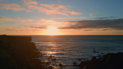 Sunset mountain hill silhouette sea coastline. Drone view dark cliffs calm ocean