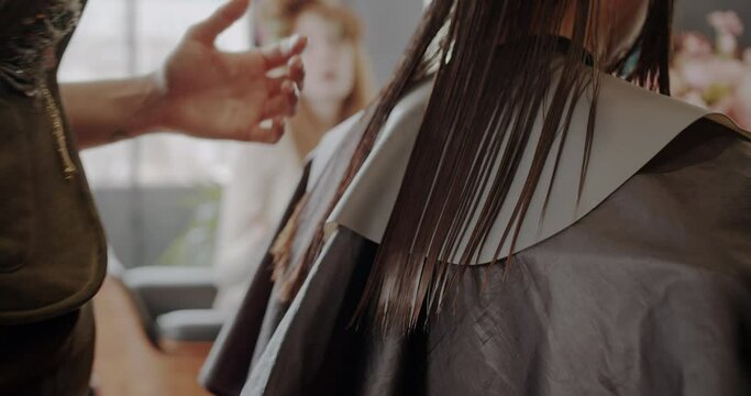 Cutting the hair of a beautiful brunette lady in hairstyling studio, close up, trucking motion