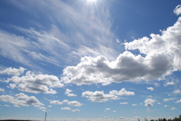 Sky landscape on a summer day. On a clear sunny day, multi-level clouds, cirrus high and cumulus low, slowly float in the light blue sky. Clouds of different shapes and sizes.
