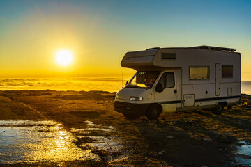 Rv camper in mountains above clouds at sunrise