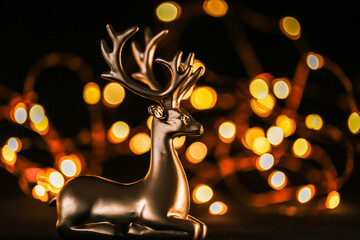 Christmas glowing wallpaper with golden deer and golden bokeh on a black background.