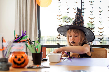 Children's Halloween party. A girl in a witch costume makes crafts for decorating a house on...