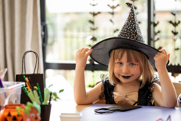 Children's Halloween party. A girl in a witch costume makes crafts for decorating a house on...