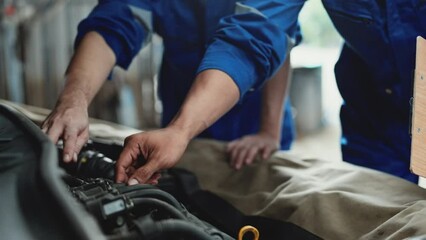 Car mechanic senior training apprentice to checking car engine at garage. - Powered by Adobe