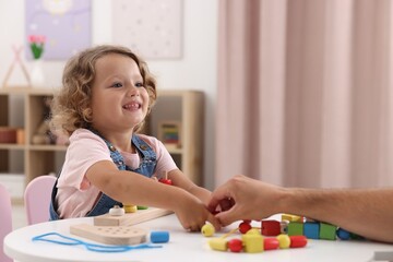 Motor skills development. Father and daughter playing with stacking and counting game at table indoors