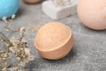 Beautiful aromatic bath bomb and gypsophila flowers on light grey table, closeup