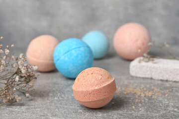 Beautiful aromatic bath bombs and gypsophila flowers on light grey table, space for text