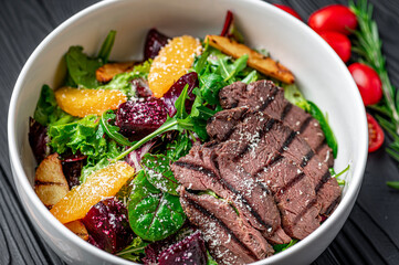 Salad with roast beef and caramelized beets with orange fillet, potatoes, parmesan, salad mix and olive oil