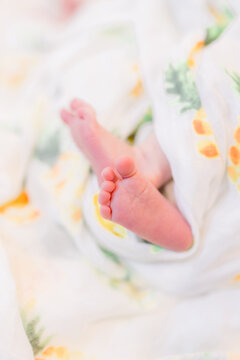 A close up of adorable newborn baby feet curled up with the foot faced out showing off all the tiny toes.