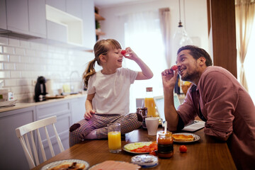 Young girl playing with vegetables with dad in the kitchen