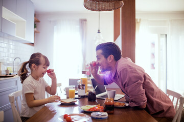 Young girl playing with vegetables with dad in the kitchen